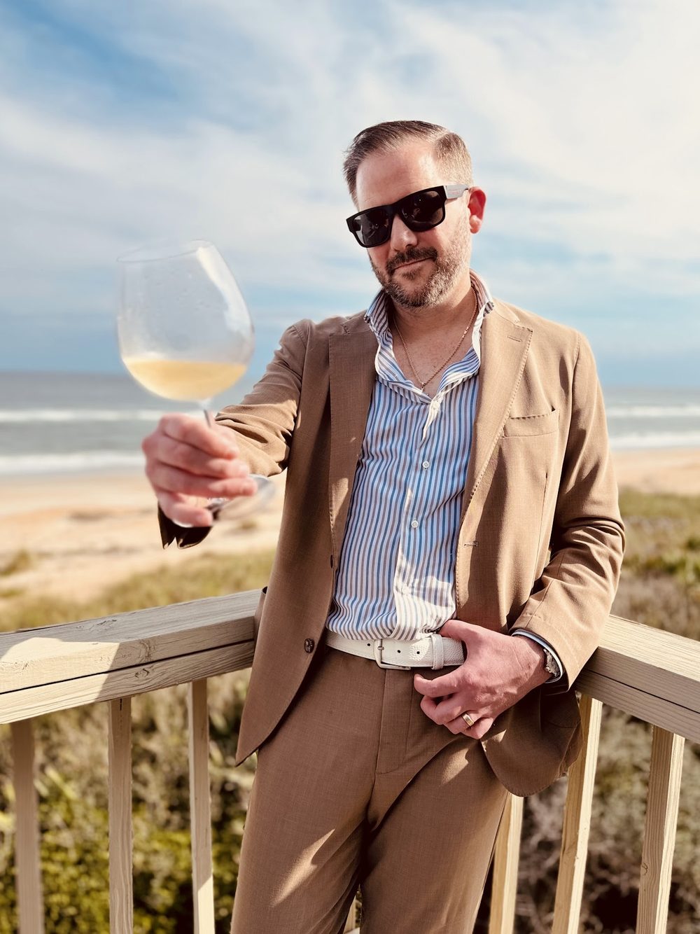 A Button Up operator in a tailored suit on a beachfront balcony